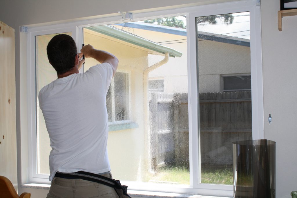 A Pacific Tint installer adding window film to a residential home.