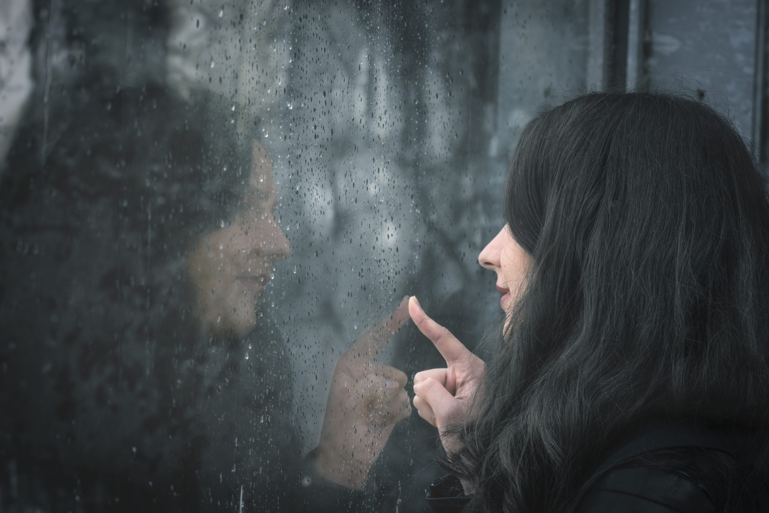 Woman and her reflection on rainy window to illustrate History of Window Tint And Today’s Modern Tinting