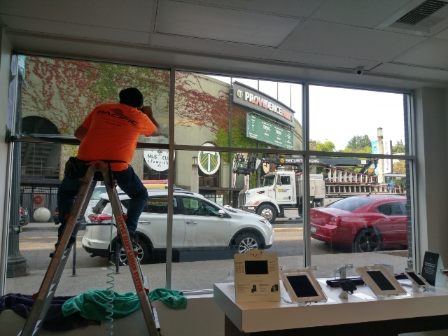 A crew member installing window tint for a business across the street from Providence Park