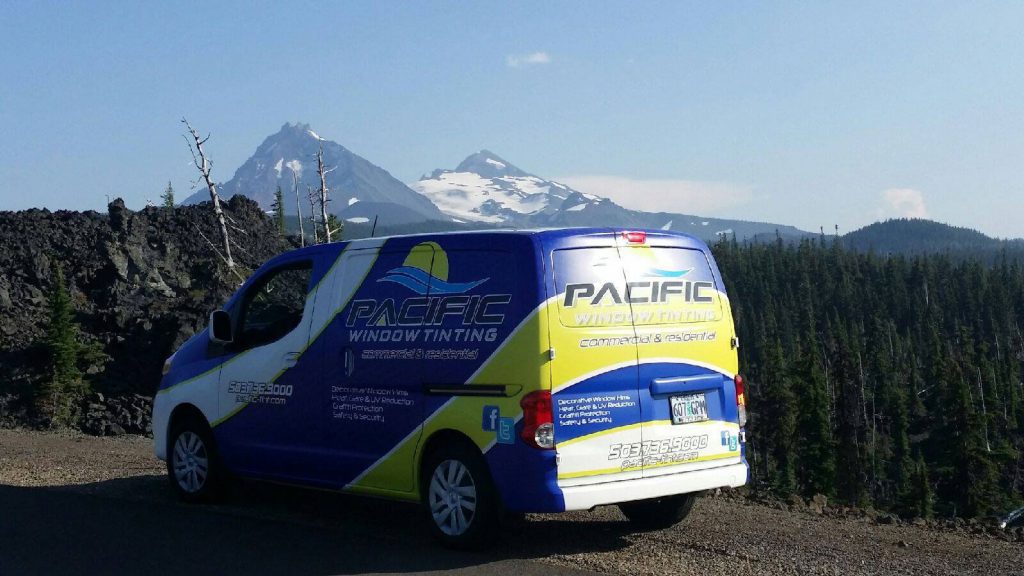 Pacific Window Tinting van on the road with mountains in the background.