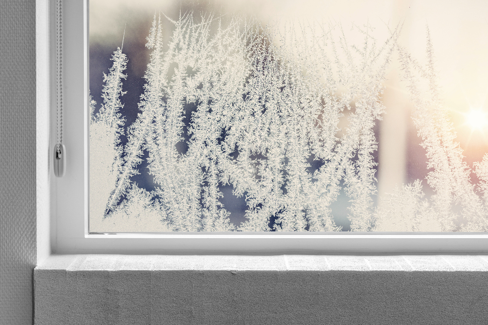 Frost forming in the lower corner of a window to help illustrate How Much Heat Do Windows Let In