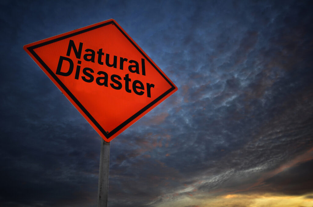 A "Natural Disaster" sign in front of dark clouds